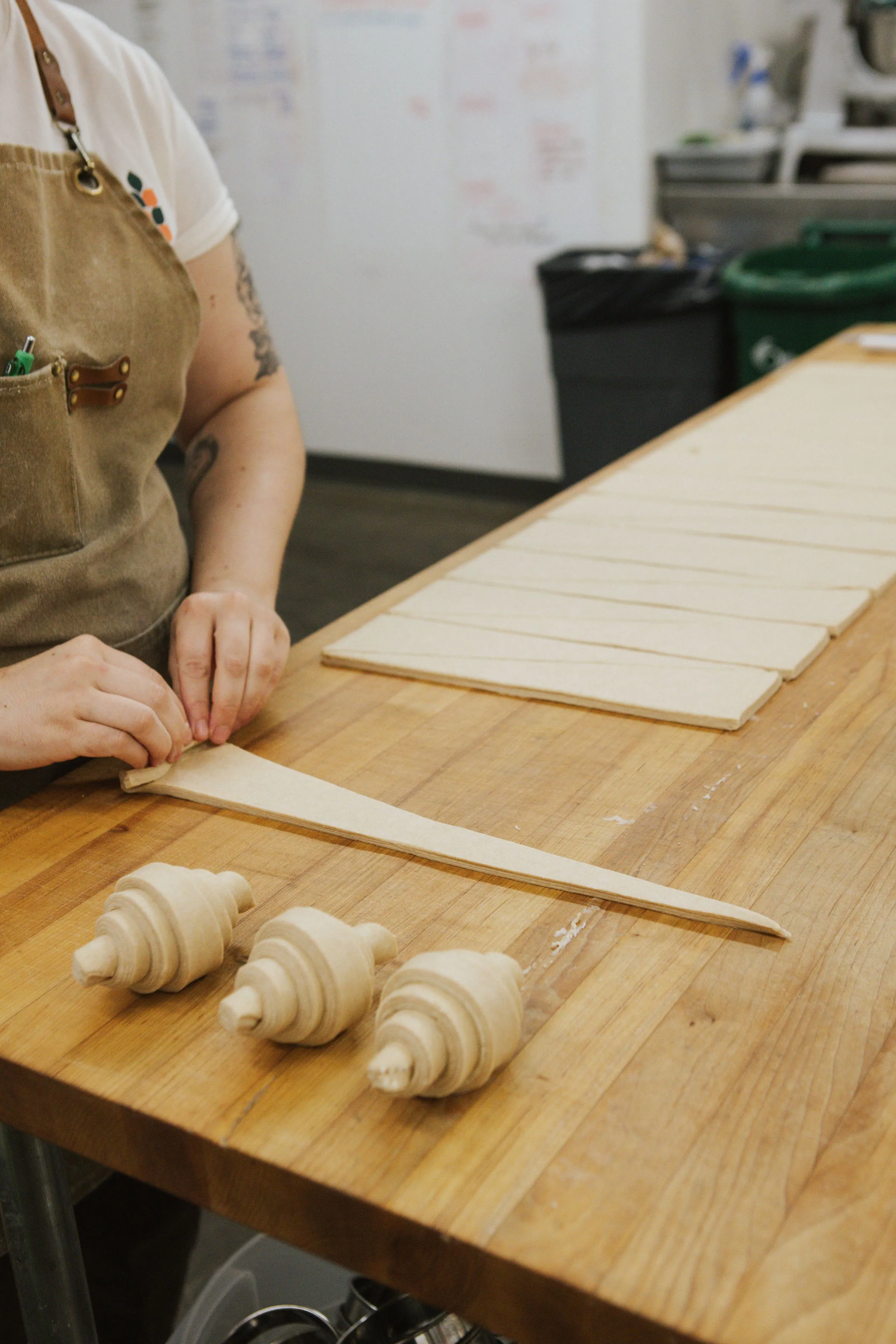 A wooden table with croissants being made