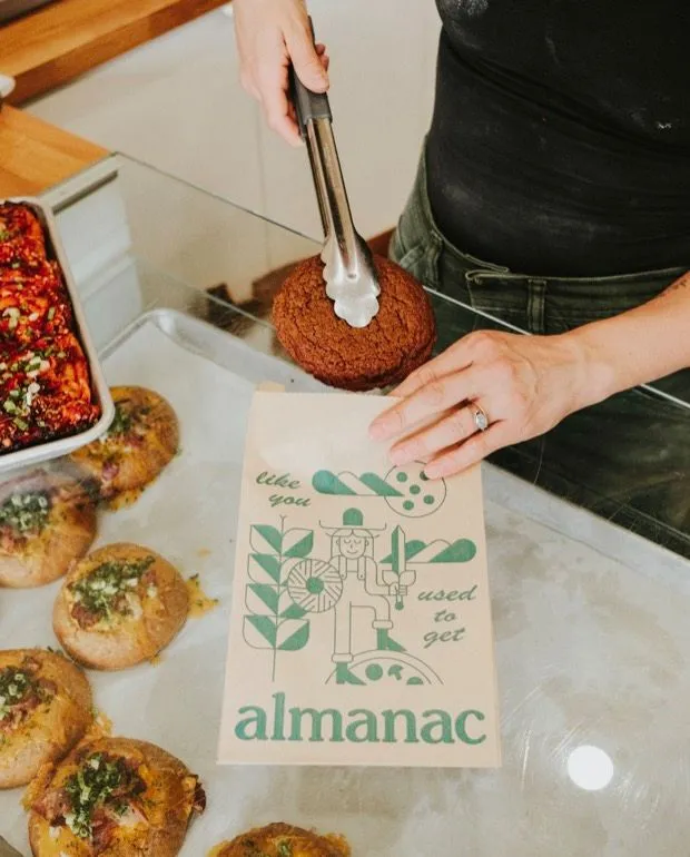 A baker bagging a pastry at the Almanac counter.